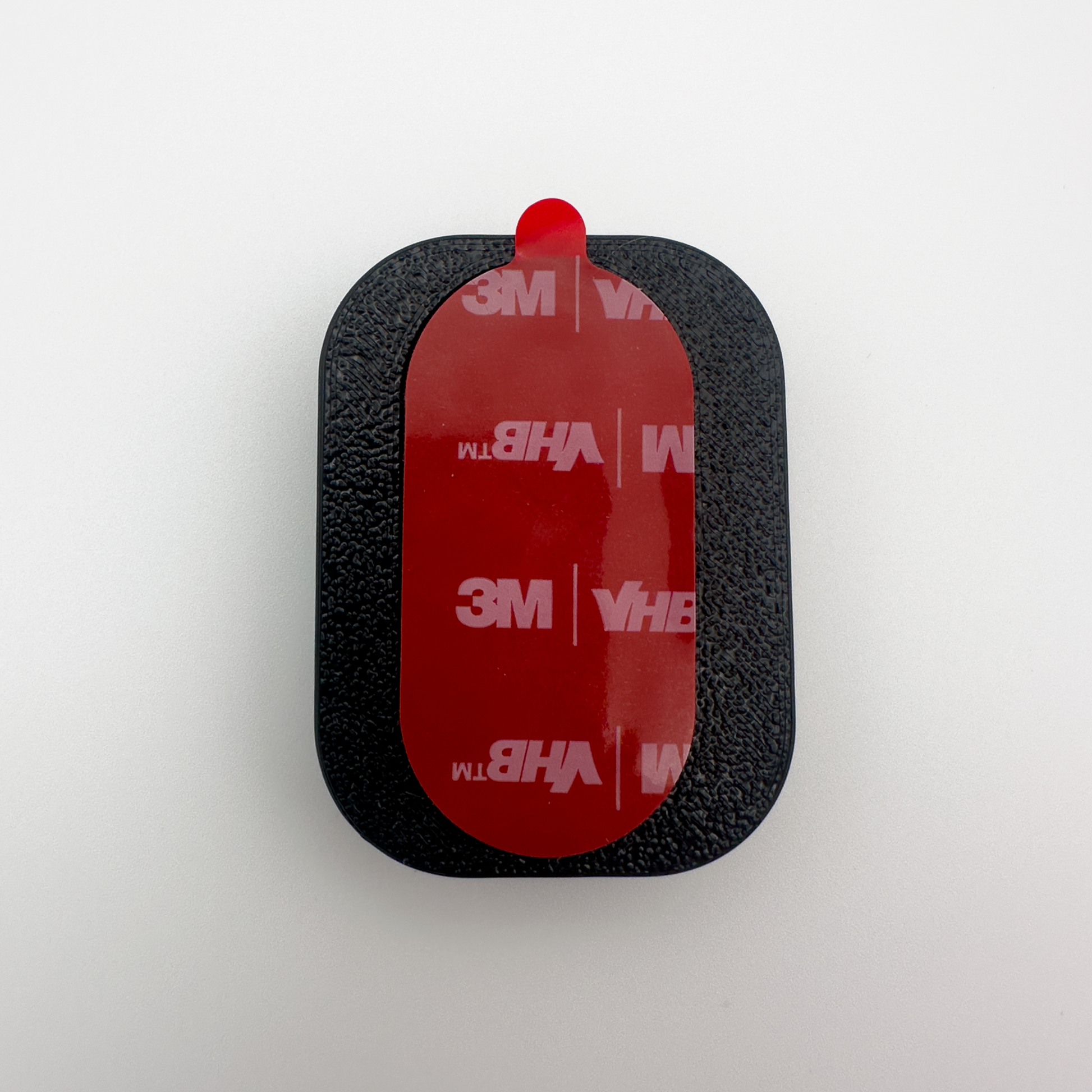 Black rectangular object with red adhesive strip on a white background